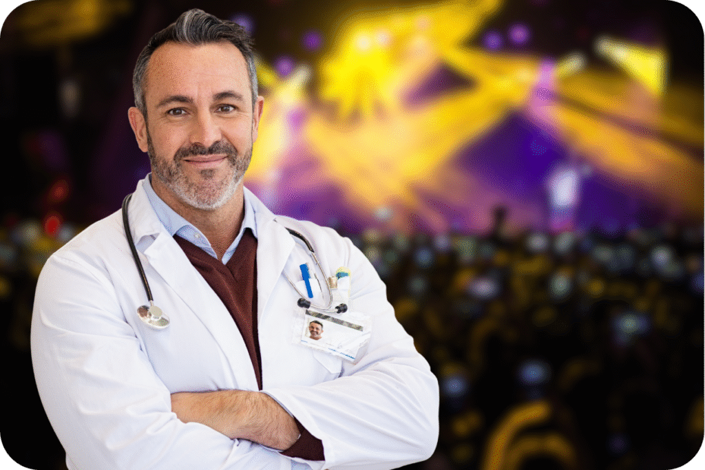 Médico em frente a um palco de show/festival de música, representando a equipe de segurança e atendimento médico em eventos.